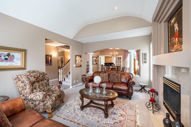 Living area with decorative columns, arched walkways, a fireplace, and vaulted ceiling | Image 10