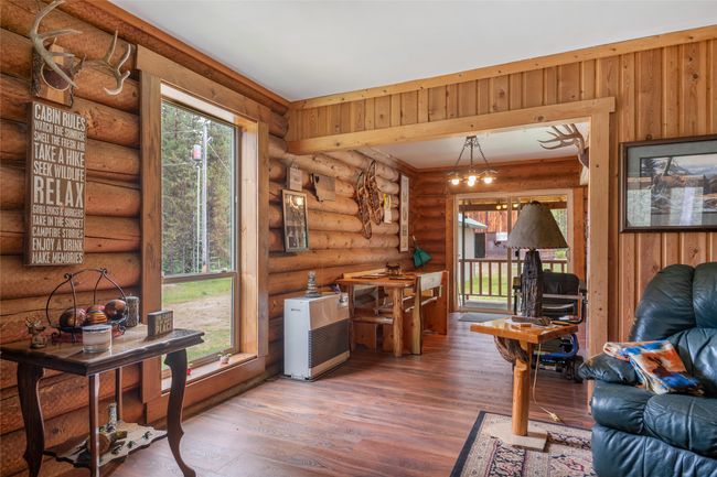 Living area featuring wood finished floors, heating unit, log walls, and a chandelier | Image 34