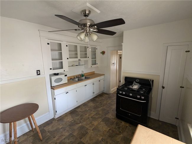Second-Floor Kitchen featuring black gas range, a textured ceiling, sink, ceiling fan, and white cabinetry | Image 23