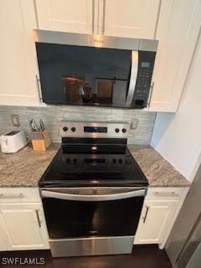 Kitchen with white cabinets, stainless steel appliances, backsplash, and light stone counters | Image 8