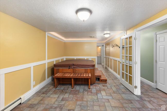Dining room with baseboards, a textured ceiling, crown molding, baseboard heating, and french doors | Image 27