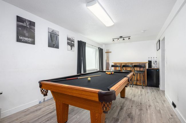 Playroom featuring wood finished floors, billiards table, a bar, baseboards, and a textured ceiling | Image 29