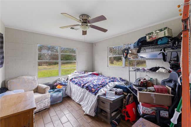 Bedroom featuring ceiling fan, crown molding, and brick wall | Image 9