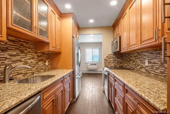 Kitchen featuring tasteful backsplash, light stone counters, a sink, and stainless steel appliances | Image 11