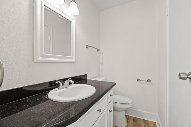 The primary bathroom is an en-suite half bath and features granite countertops, a new vanity, custom mirror, and all new fixtures. The large primary walk in closet is to the right. | Image 8