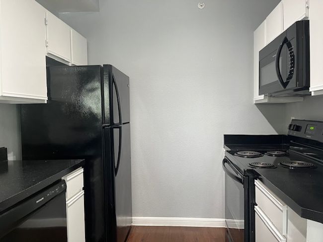 Kitchen with black appliances, baseboards, white cabinetry, and dark countertops | Image 11