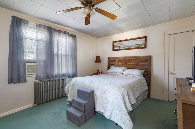Carpeted bedroom featuring ceiling fan, ornamental molding, and radiator | Image 13
