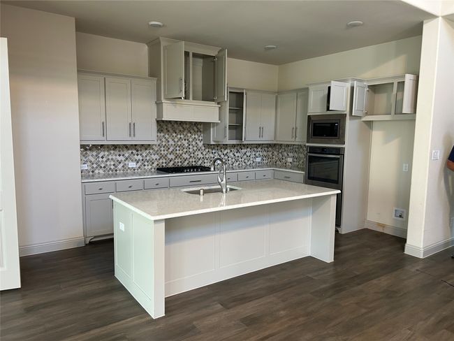 Kitchen featuring stainless steel appliances, a sink, dark wood finished floors, and tasteful backsplash | Image 18