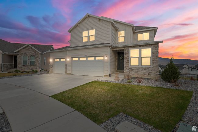 View of front of home with concrete driveway, a front lawn, stone siding, and a garage | Image 50