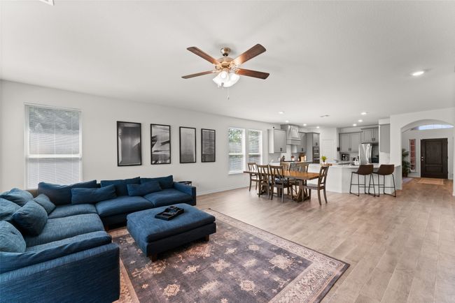 Living area with a ceiling fan, light wood-style floors, arched walkways, and recessed lighting | Image 13