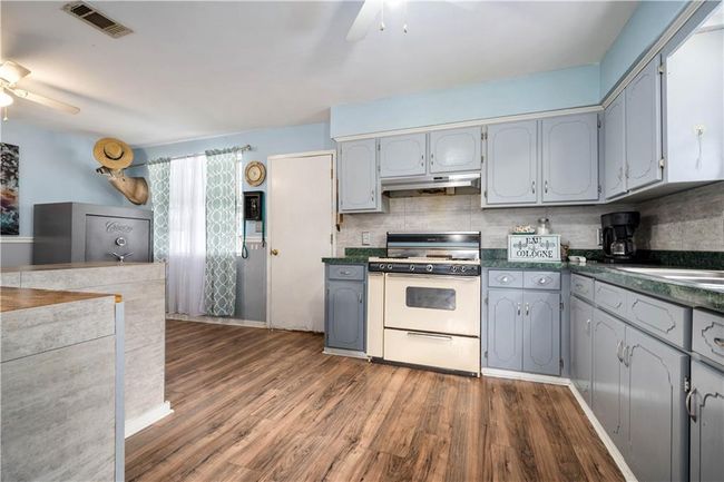 Kitchen featuring white gas range oven, a ceiling fan, under cabinet range hood, and dark countertops | Image 9