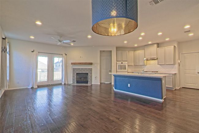 Kitchen with white oven, ceiling fan, light countertops, white cabinetry, and under cabinet range hood | Image 10