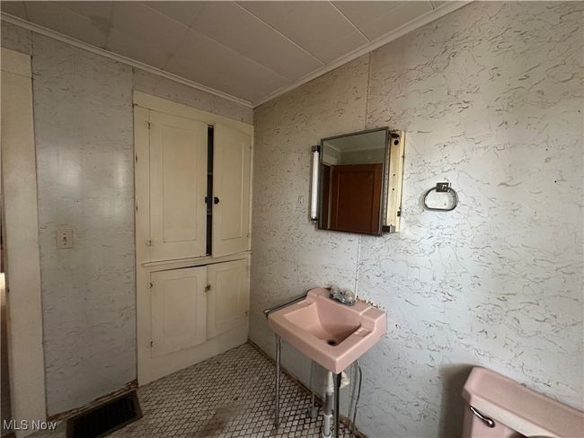Bathroom with tile patterned flooring, visible vents, toilet, ornamental molding, and a sink | Image 14