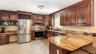 Kitchen featuring backsplash, a breakfast bar, kitchen peninsula, and appliances with stainless steel finishes | Image 3