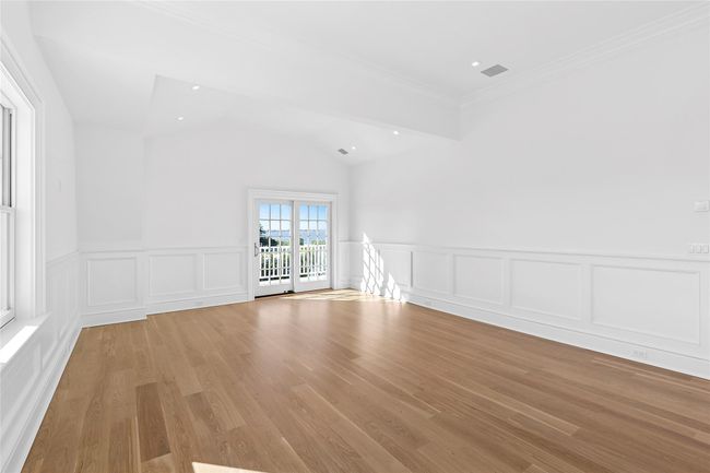 Spare room featuring a decorative wall, light wood-type flooring, wainscoting, crown molding, and vaulted ceiling | Image 30