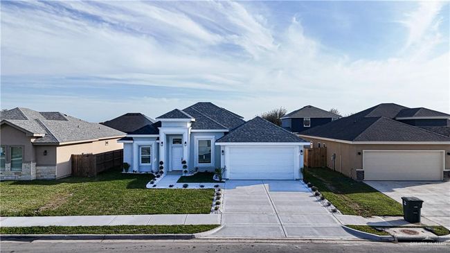 View of front of property with driveway, a garage, fence, a front lawn, and stucco siding | Image 12