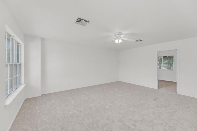 Empty room with visible vents, ceiling fan, and light colored carpet | Image 23