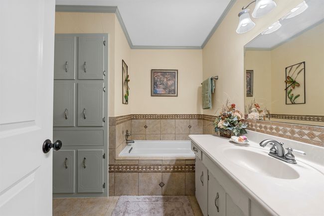Full bath featuring vanity, a garden tub, tile patterned floors, and crown molding | Image 23