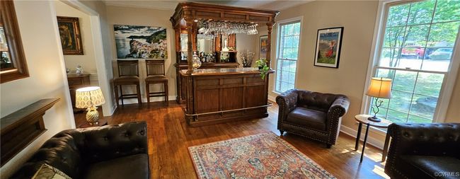 Living area with crown molding, hardwood / wood-style floors, and a bar setup for entertaining | Image 14