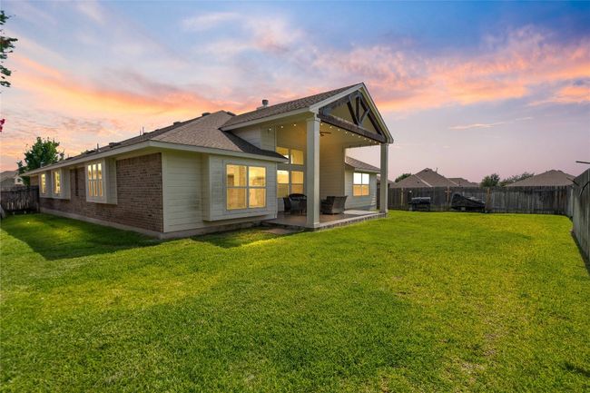 Rear view of house with a patio, a fenced backyard, brick siding, and a shingled roof | Image 26