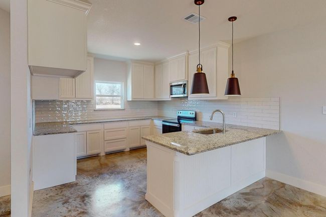 Kitchen with a peninsula, appliances with stainless steel finishes, light stone countertops, backsplash, and recessed lighting | Image 10