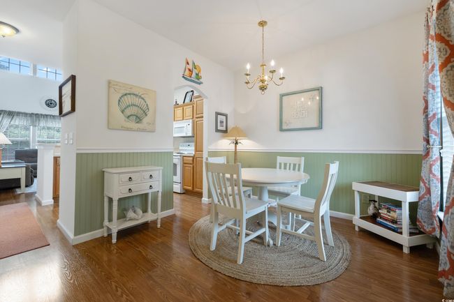 Dining space featuring wainscoting, wood finished floors, a chandelier, and arched walkways | Image 12