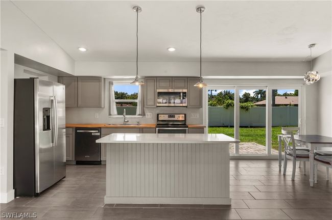 Kitchen with appliances with stainless steel finishes, sink, pendant lighting, gray cabinets, and a kitchen island | Image 19