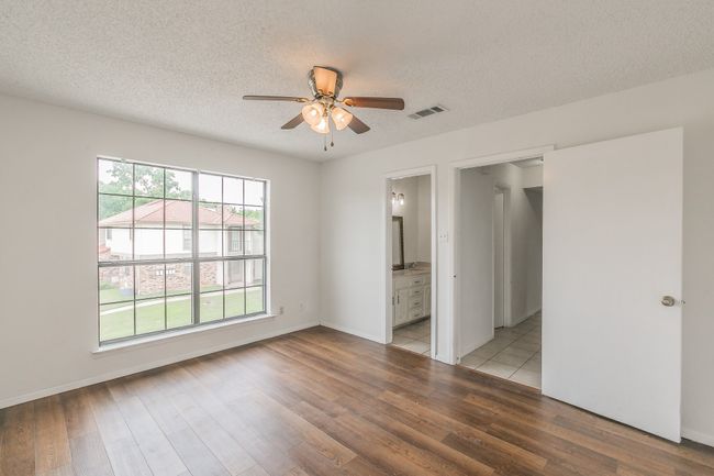 Unfurnished bedroom featuring light wood-type flooring, a textured ceiling, connected bathroom, a ceiling fan, and baseboards | Image 15