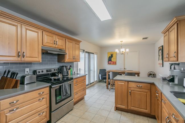 Unit 4900 Another View of Kitchen with hanging light fixtures, stainless steel electric range oven, backsplash, and kitchen peninsula | Image 11