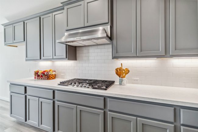 Kitchen with extractor fan, gray cabinets, stainless steel gas stovetop, and light countertops | Image 15