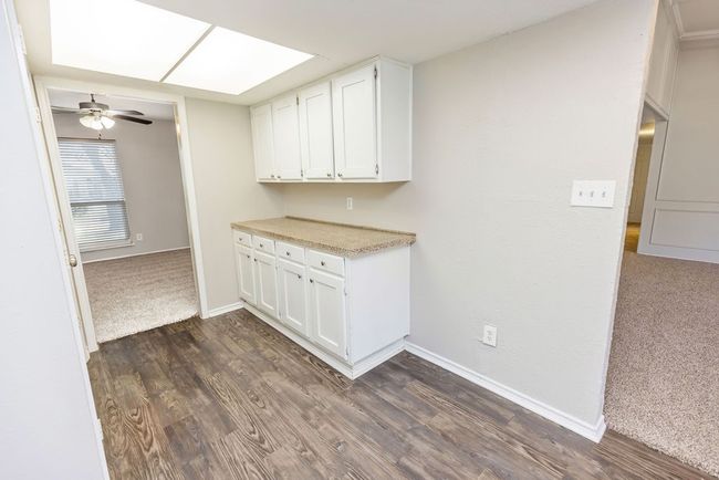 Kitchen with white cabinetry, dark wood-style floors, light countertops, and a ceiling fan | Image 12