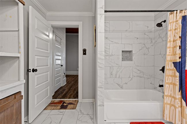 Bathroom with marble finish floor, baseboards, crown molding, and shower / bathtub combination with curtain | Image 28