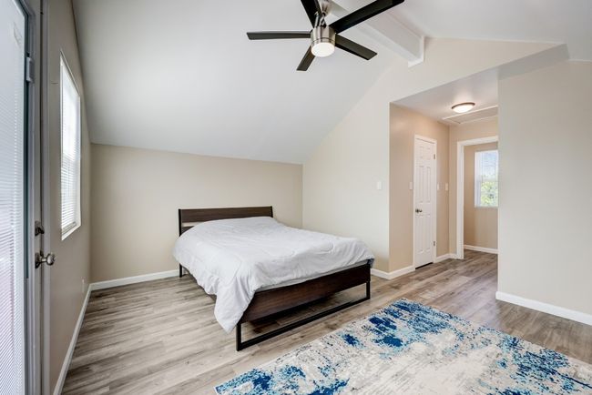 Bedroom with baseboards, vaulted ceiling with beams, a ceiling fan, and wood finished floors | Image 10
