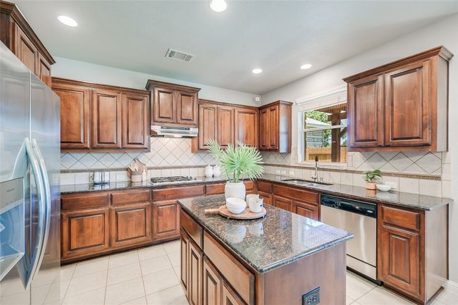 Kitchen featuring stainless steel appliances, recessed lighting, light tile patterned floors, dark stone countertops, and brown cabinets | Image 4