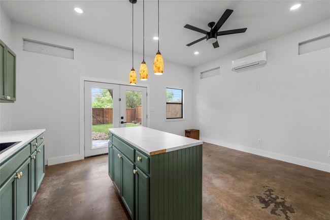Kitchen with green cabinets, a wall mounted AC, finished concrete floors, and recessed lighting | Image 33