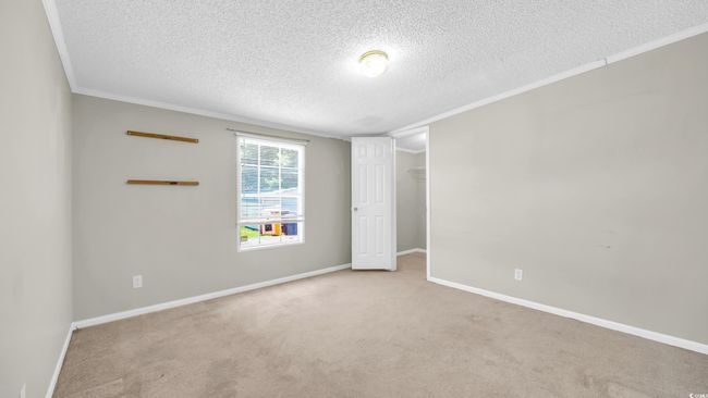 Carpeted empty room featuring a textured ceiling and crown molding | Image 13