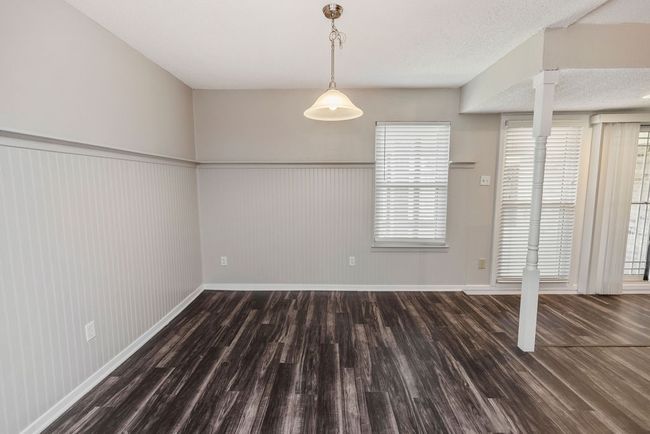 Unfurnished dining area featuring wood finished floors, a wainscoted wall, baseboards, and healthy amount of natural light | Image 13