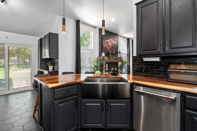 Kitchen with sink, tasteful backsplash, wooden counters, hanging light fixtures, and stainless steel dishwasher | Image 5