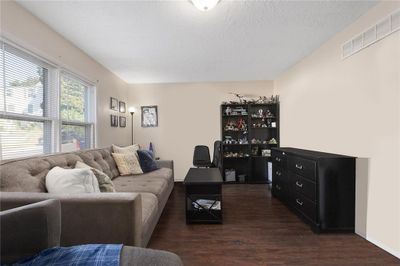 Living room featuring dark hardwood / wood-style flooring and a textured ceiling | Image 2