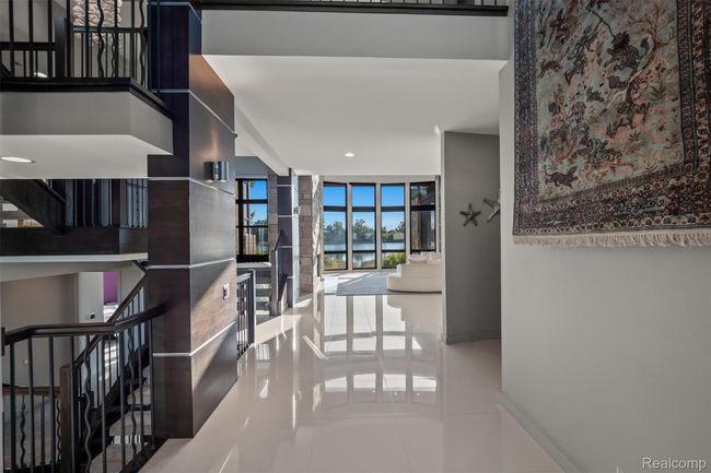 Hallway featuring tile patterned floors, stairs, a water view, floor to ceiling windows, and recessed lighting | Image 5
