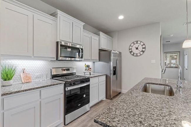 Kitchen with stainless steel appliances, white cabinetry, decorative backsplash, and recessed lighting | Image 6