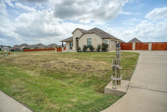 View of front of house with concrete driveway, stone siding, a gate, a garage, and a shingled roof | Image 34