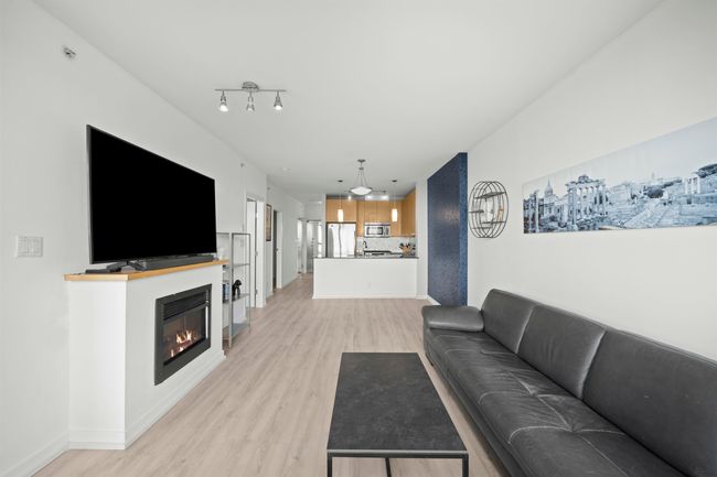 Living room with light wood finished floors, a glass covered fireplace, and baseboards | Image 5