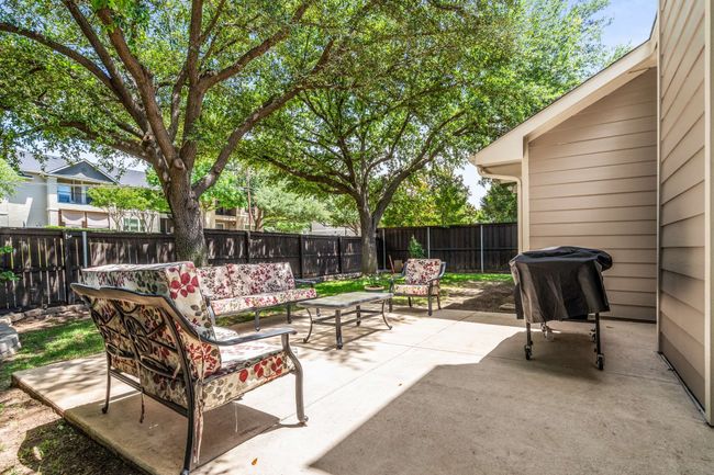 Fenced backyard featuring outdoor lounge area and an extended patio in a shady yard. | Image 34
