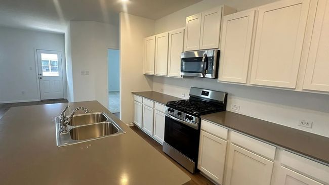 Kitchen featuring appliances with stainless steel finishes, white cabinetry, dark countertops, and dark wood-style flooring | Image 9