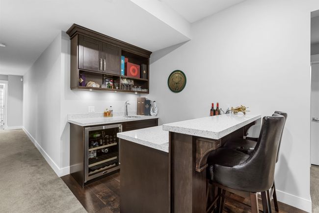 Bar with wine cooler, dark wood-type flooring, a sink, baseboards, and indoor wet bar | Image 26