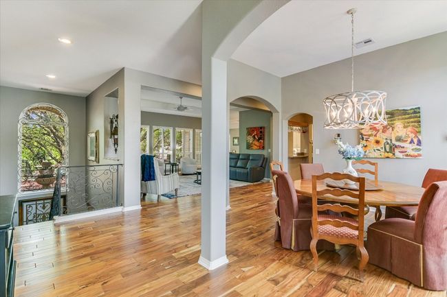 Dining area with arched walkways, a chandelier, light wood finished floors, recessed lighting, and baseboards | Image 7