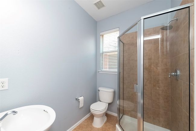 Bathroom with visible vents, toilet, a stall shower, a sink, and tile patterned flooring | Image 25