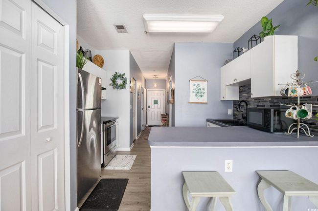 Kitchen with appliances with stainless steel finishes, a sink, light wood-style floors, white cabinets, and a peninsula | Image 4