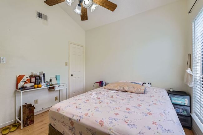 Bedroom with visible vents, baseboards, light wood finished floors, a ceiling fan, and high vaulted ceiling | Image 20